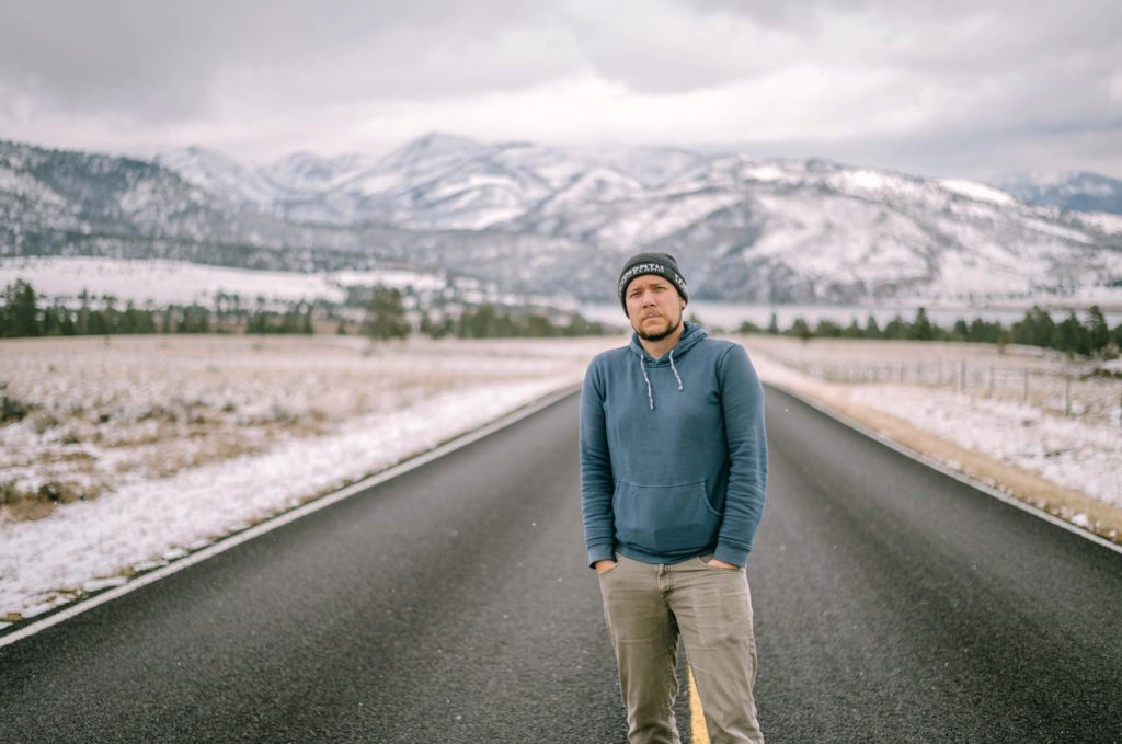 Man stands in the middle of a road looking at the camera
